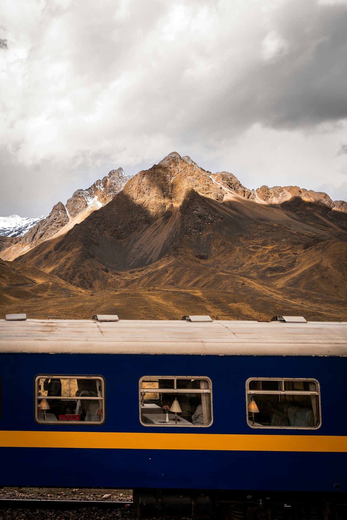 Blue train passing through a rugged Andes mountain landscape, Peru