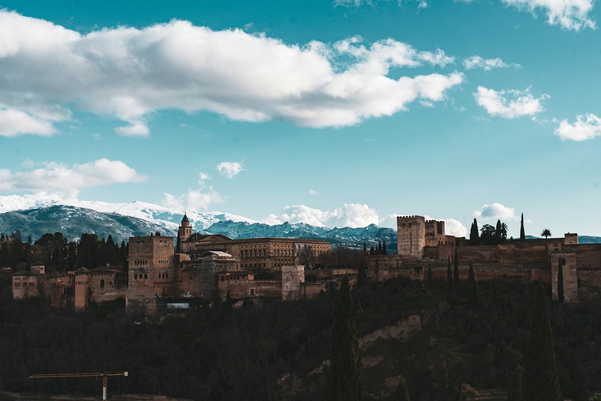 Alhambra fortress on a hilltop with snowy Sierra Nevada mountains behind