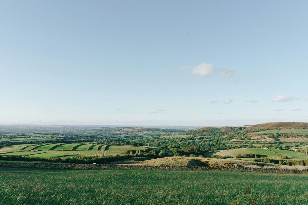 Green rolling hills of the Peak District under a wide sky