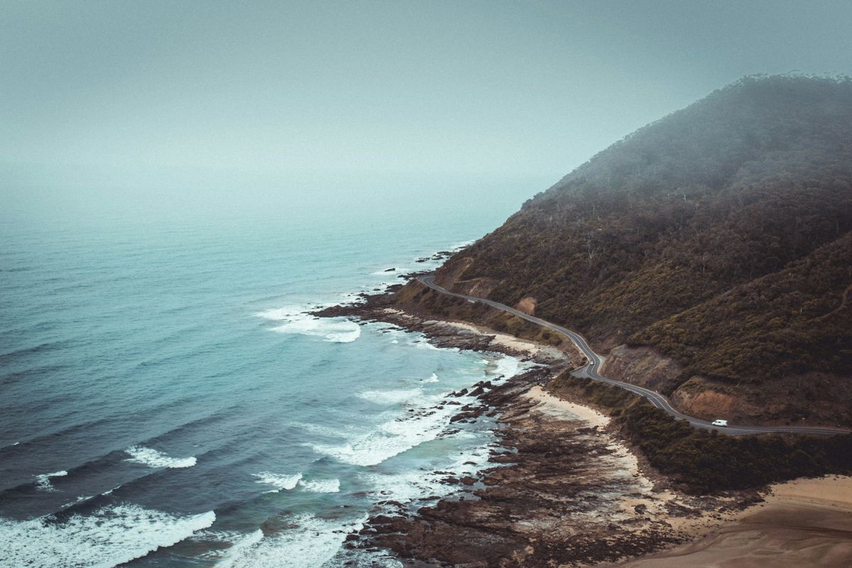 Aerial view of mountains beside the winding Great Ocean Road highway and sea