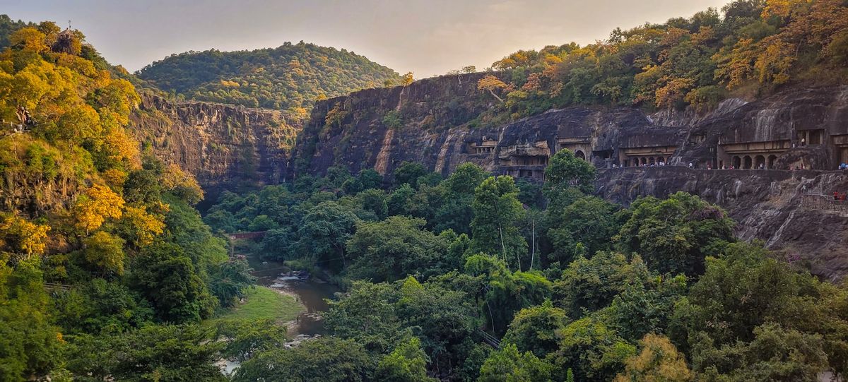 Lush green valley with the ancient Ajanta caves carved into the cliffside