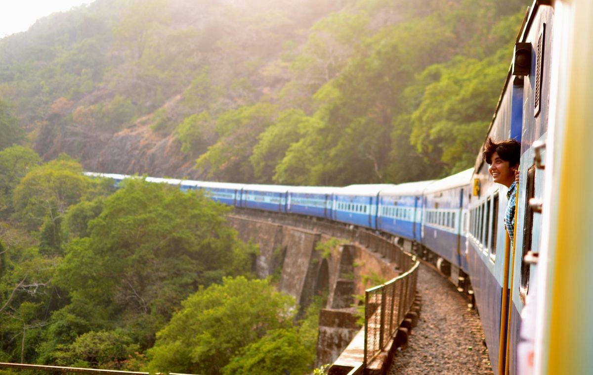 Passenger train moving through lush green hillside scenery