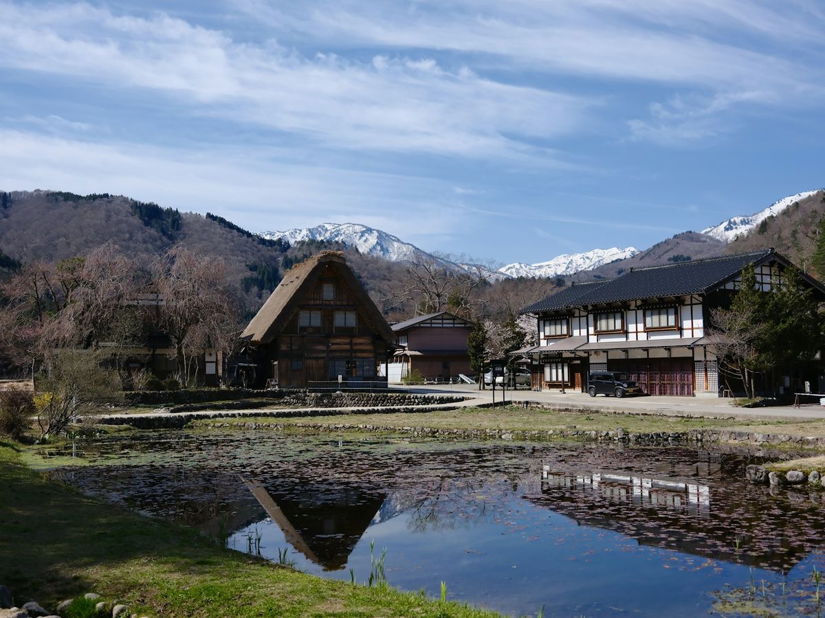 Traditional gassho-zukuri house with pond and mountains near Shirakawa-go, Hida valley