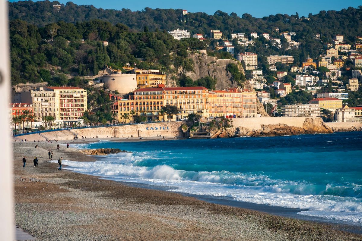People strolling on a sunny beach in Nice with turquoise water
