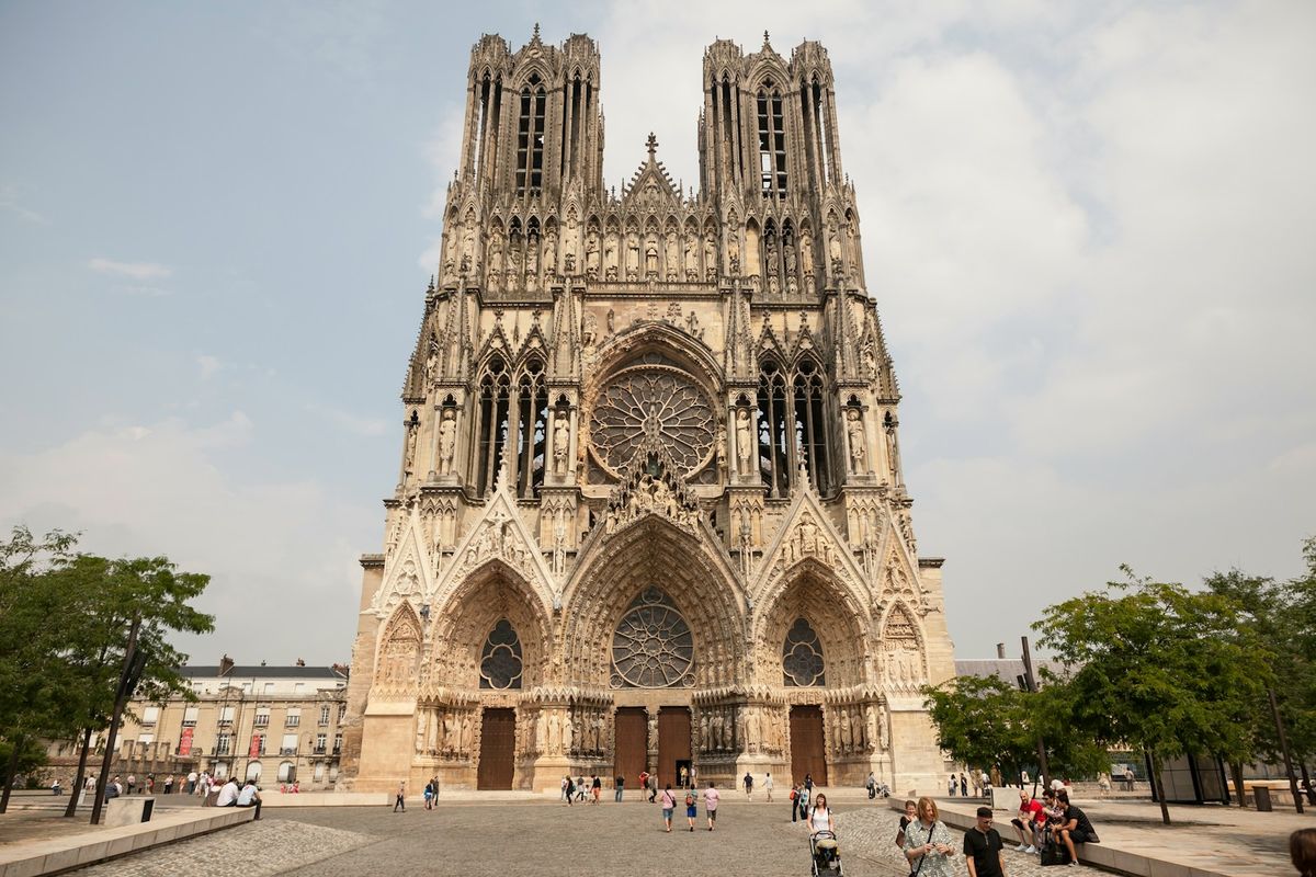 People walking near Reims historic cathedral building