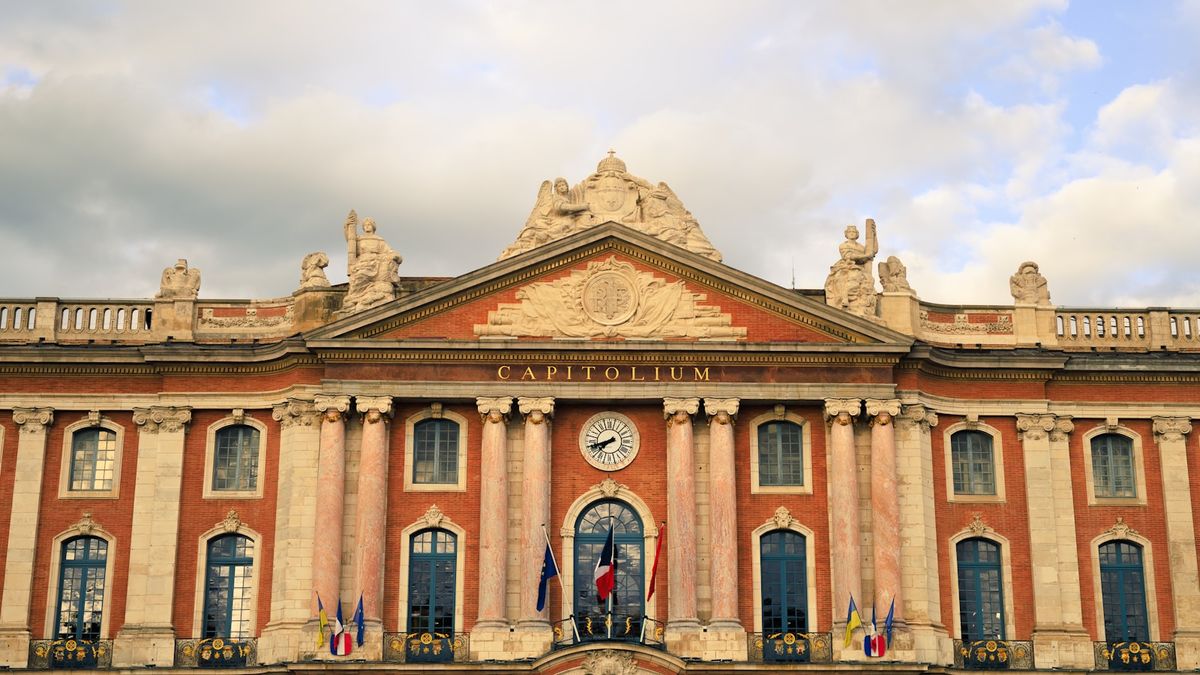 Grand classical building with flags in Toulouse Capitole square