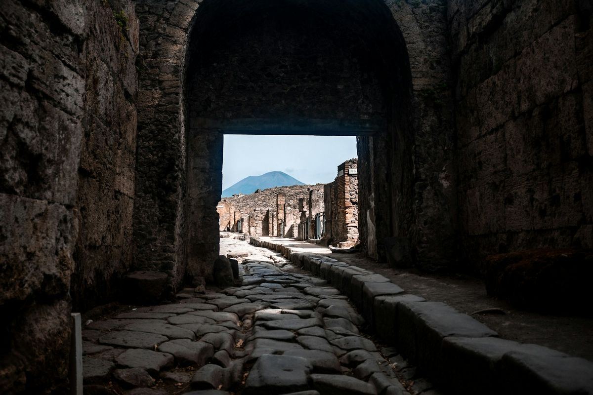Ancient stone street in Pompeii leading toward Mount Vesuvius in the distance