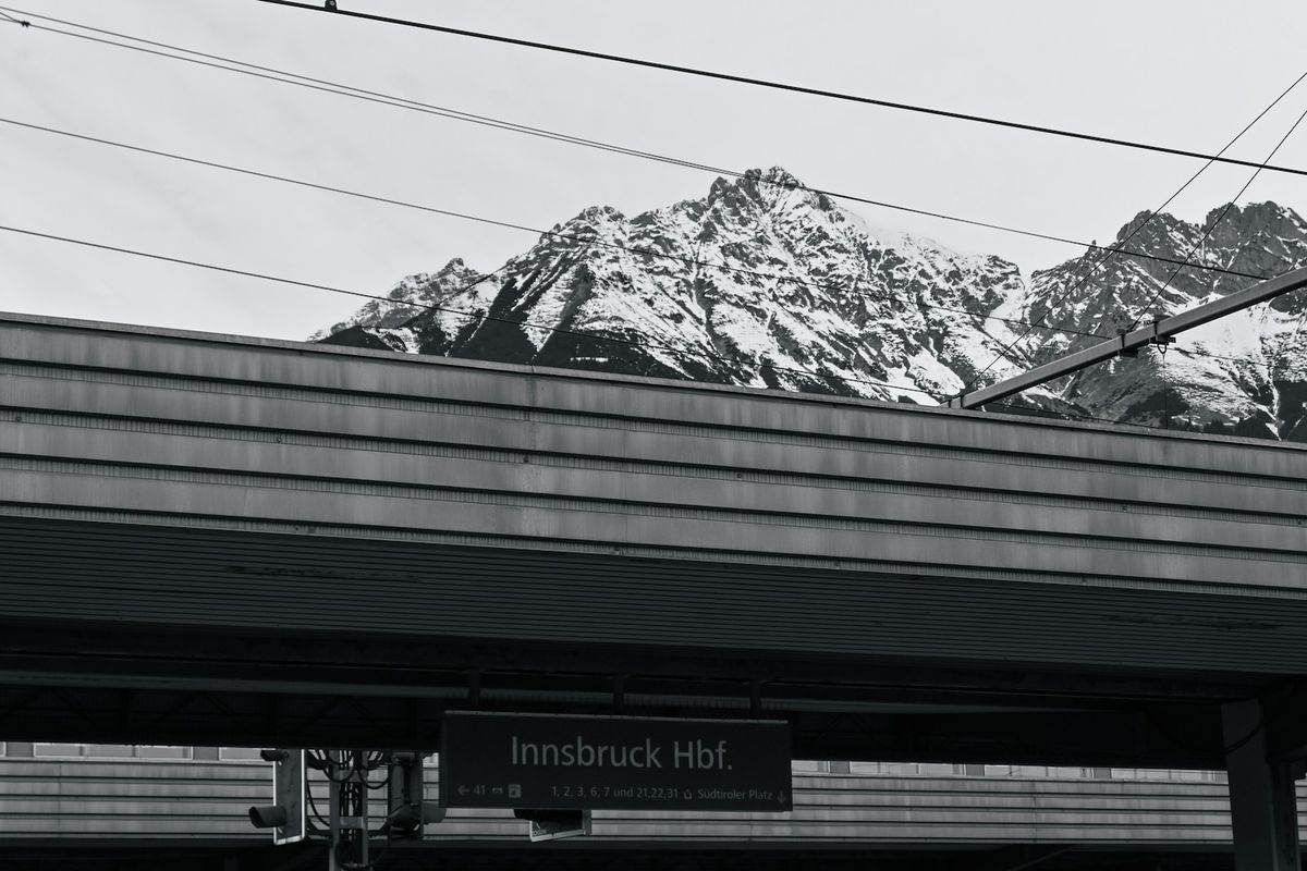 Snowy alpine mountains rise behind a train station platform