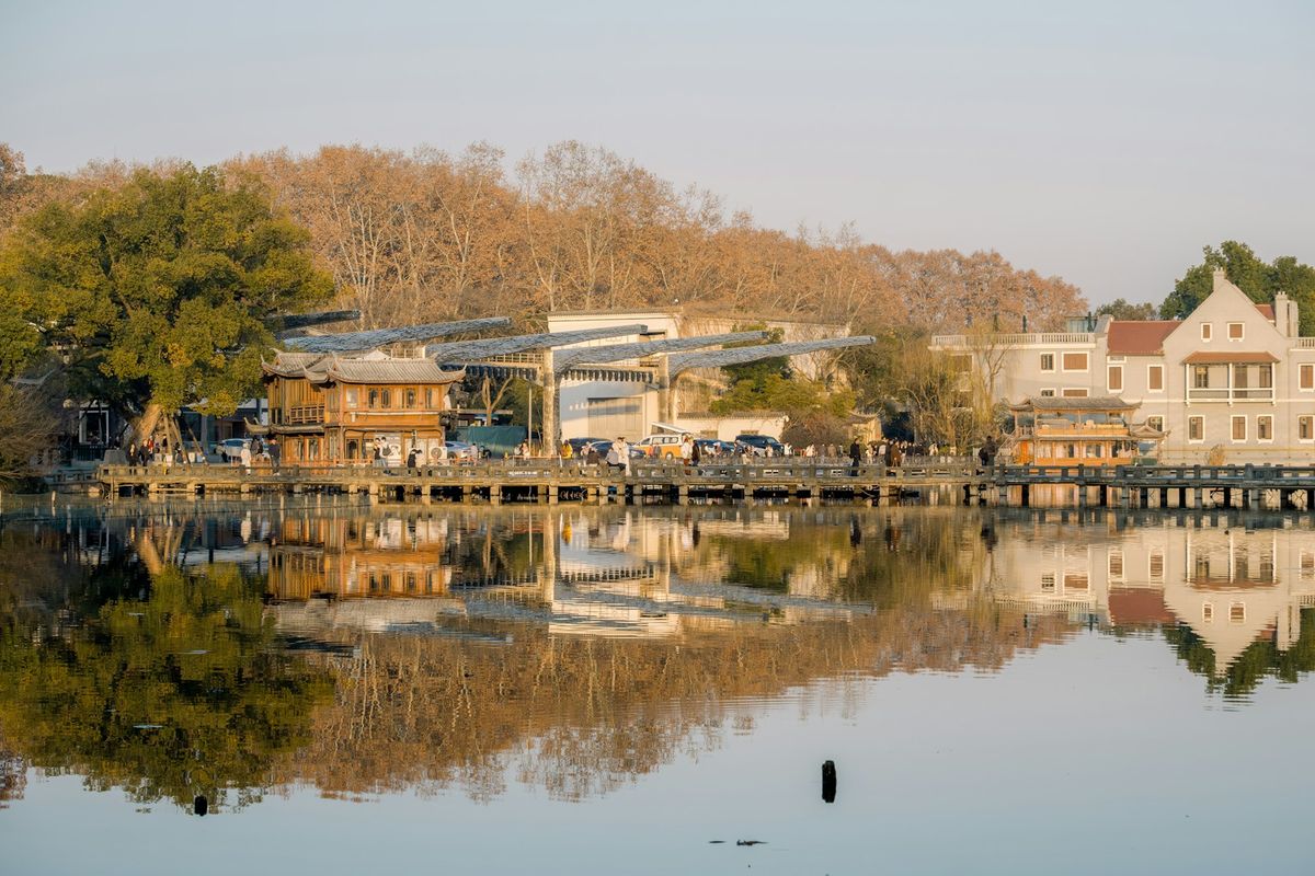 Traditional Chinese buildings reflected in calm West Lake at sunrise Hangzhou