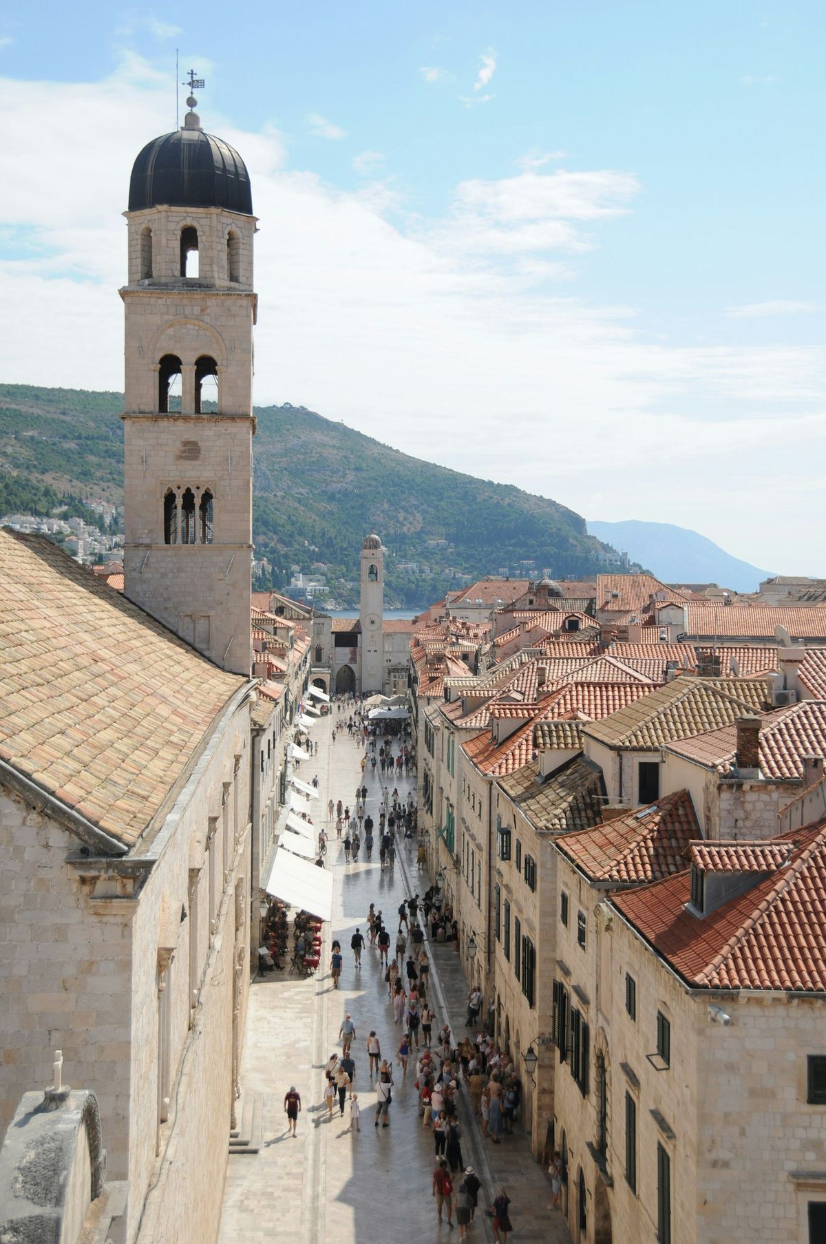 Pedestrians walking through a narrow stone-paved street in Dubrovnik old town