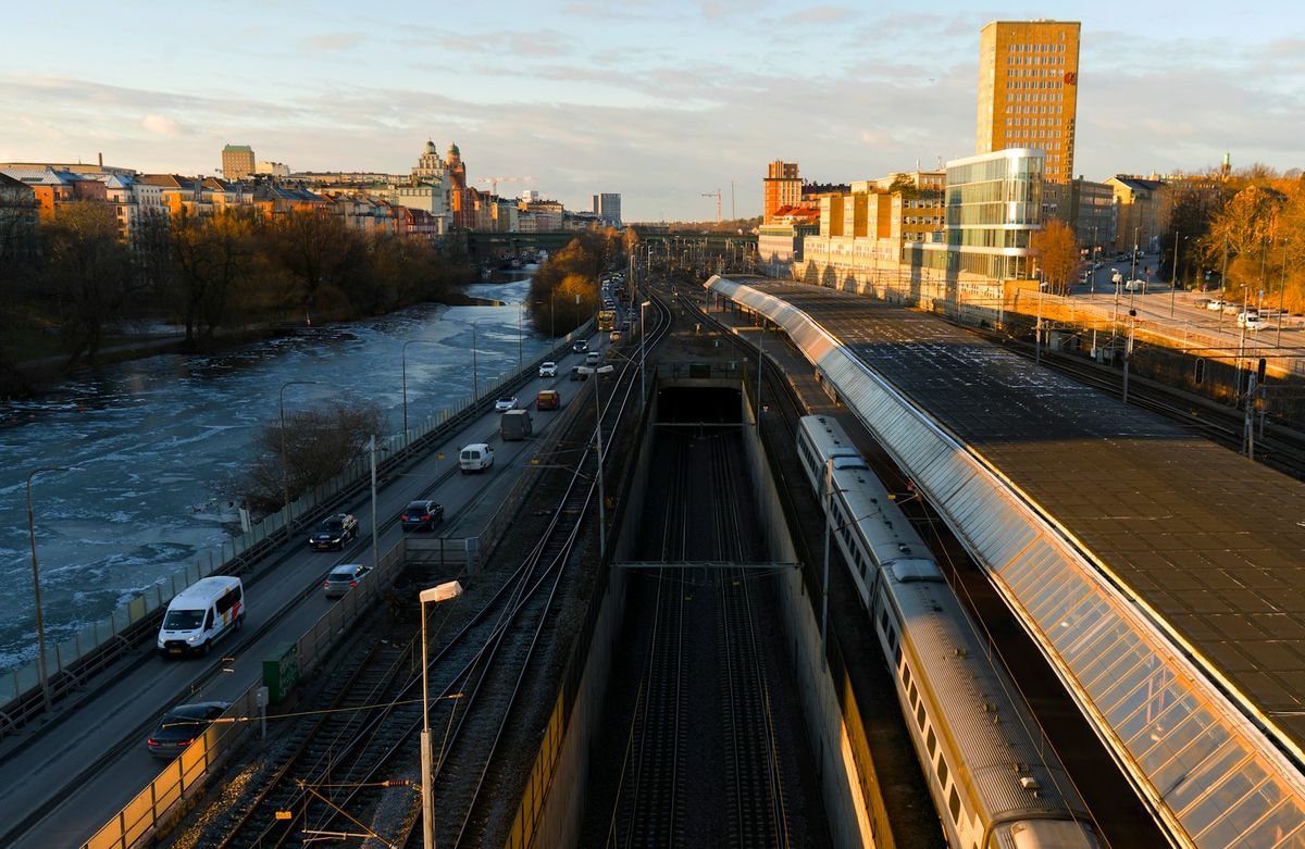 Train traveling down tracks next to a river in Sweden