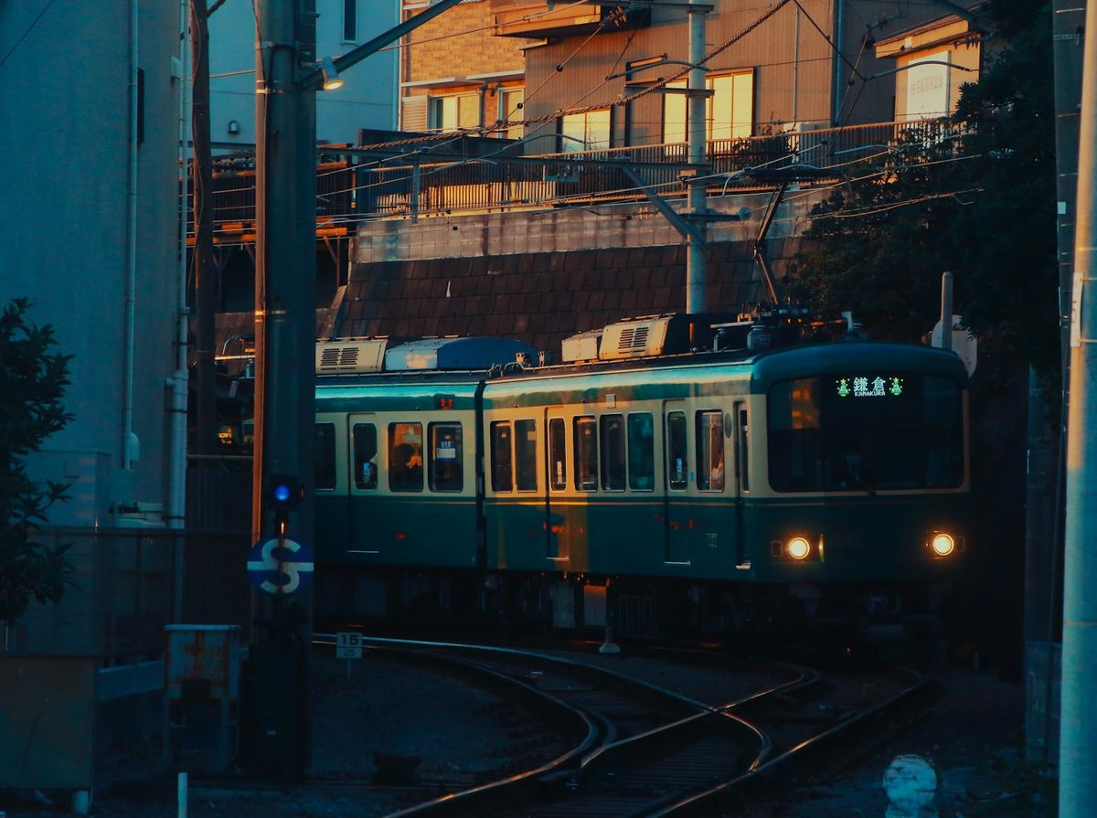 Green Enoden train travelling along the tracks near Kamakura, Japan