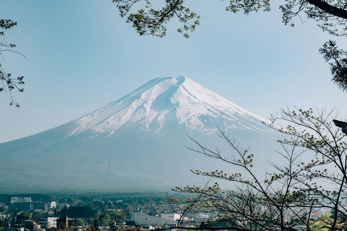 Mount Fuji seen in the distance beyond forested hills near Tokyo