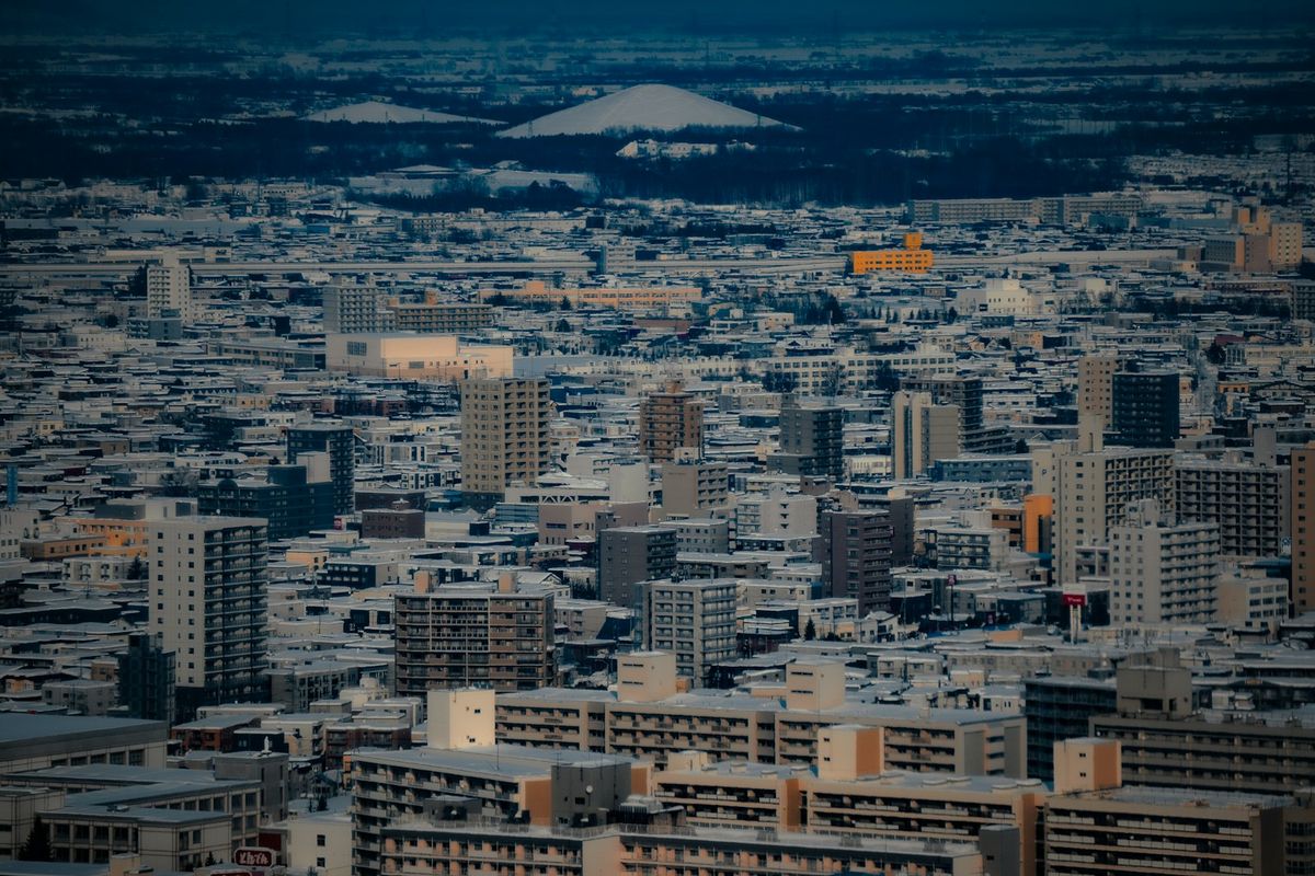 Snow-covered Sapporo city skyline with distant mountain peak in winter