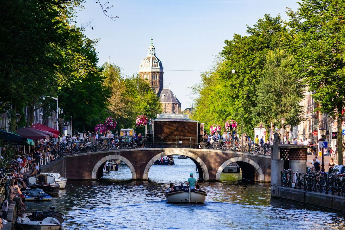 People on a boat traveling Amsterdam canal with bridge