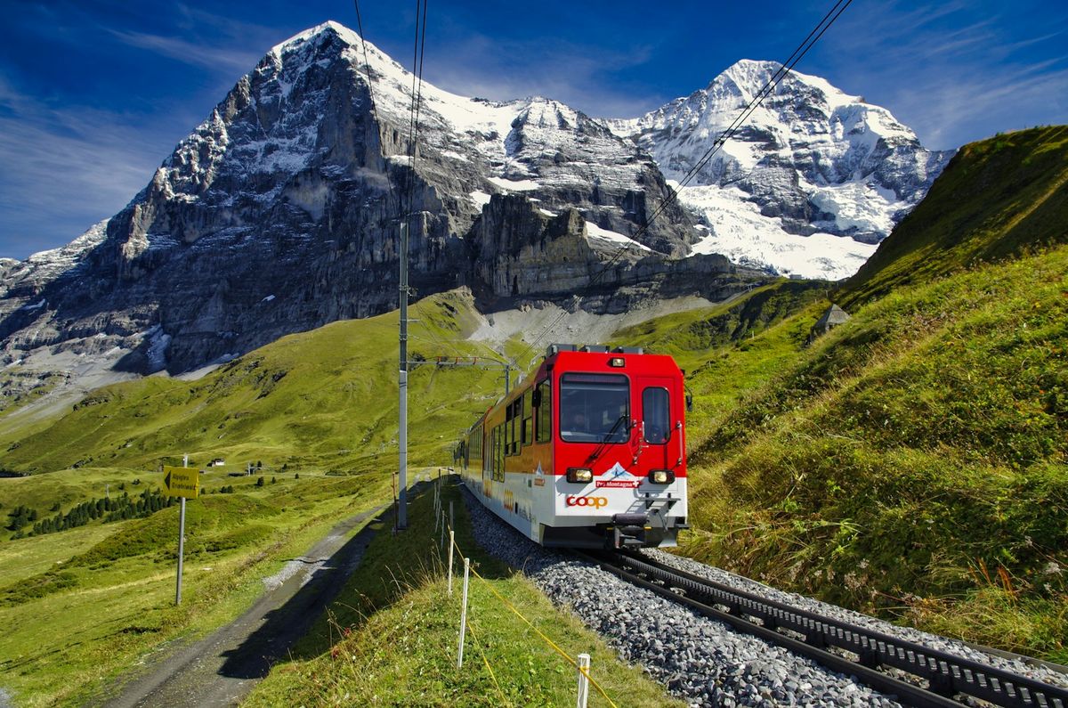 Red and white train near snow-covered Austrian Alpine mountain
