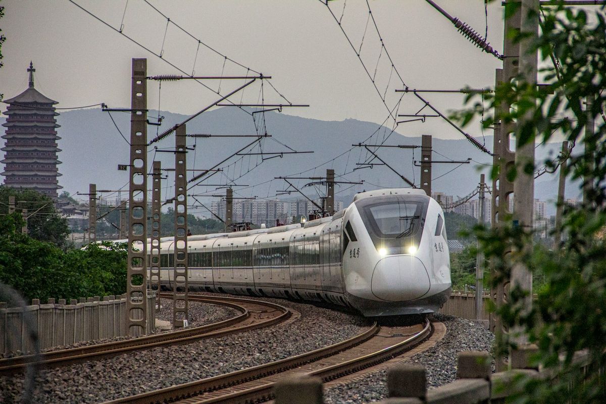 A Chinese train travelling alongside forest scenery