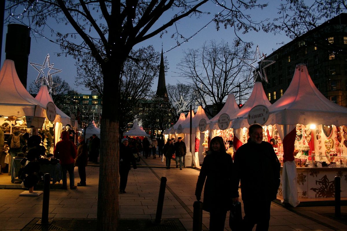 Visitors walking along a European street lined with Christmas market stalls
