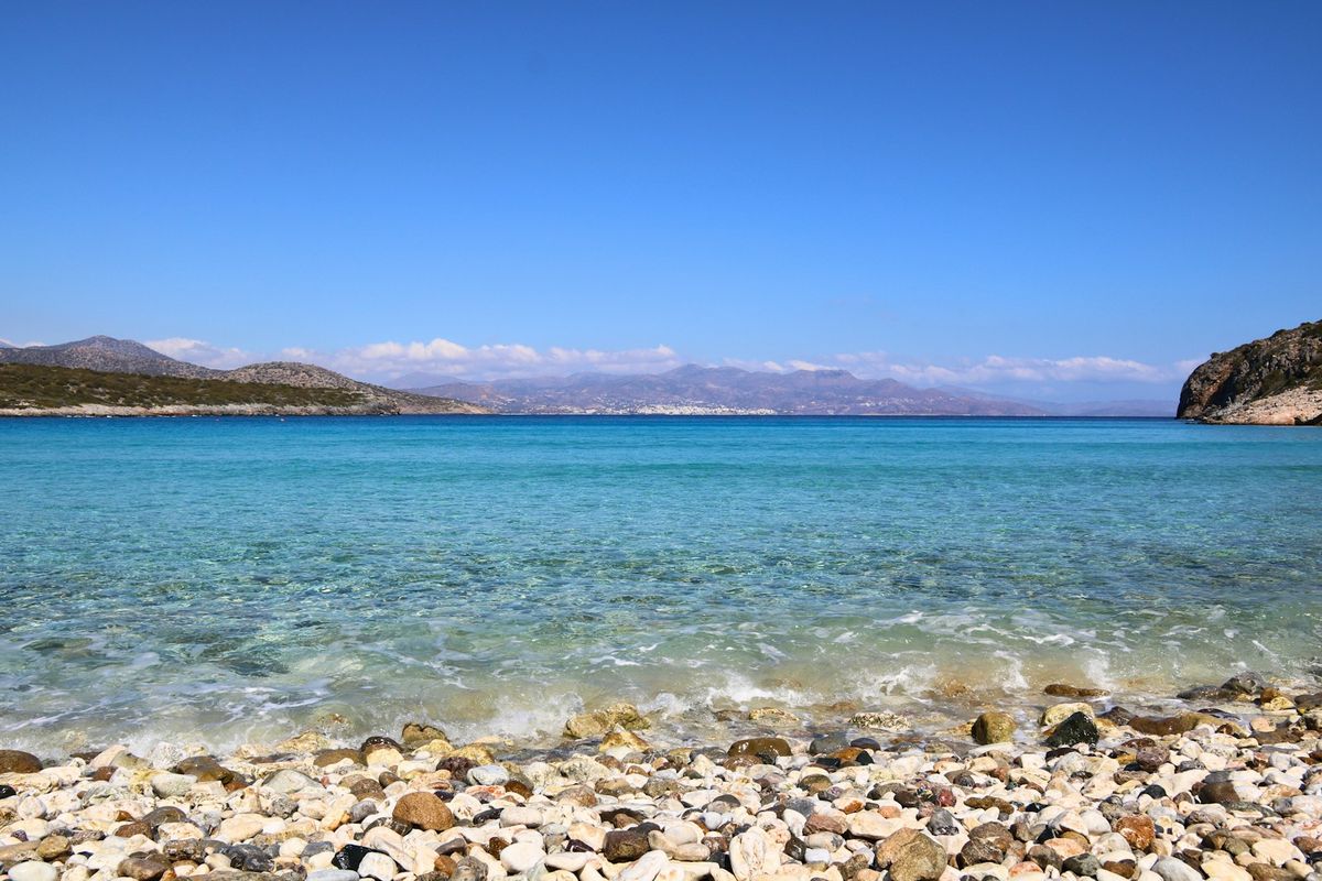 Rocky Greek beach with clear blue water and mountains