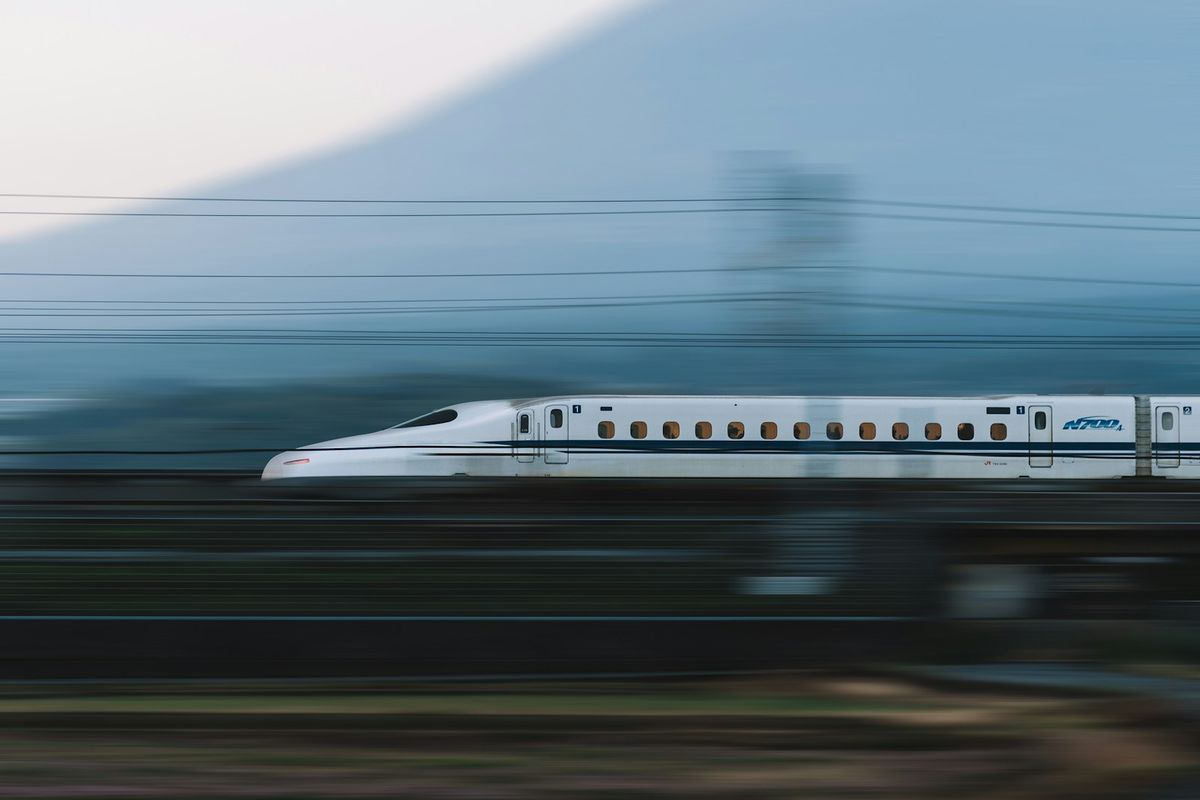 White Shinkansen bullet train speeding past Mount Fuji
