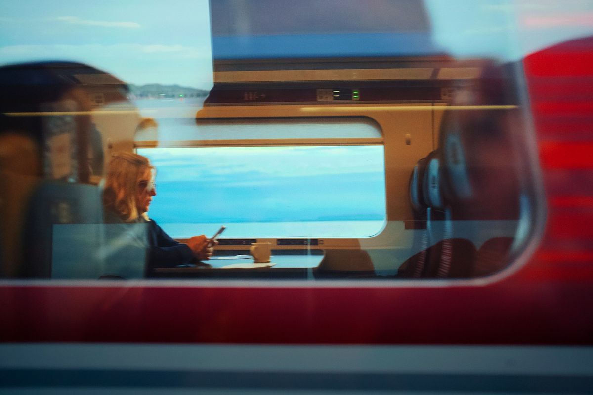 Man looking out a train window at the sea