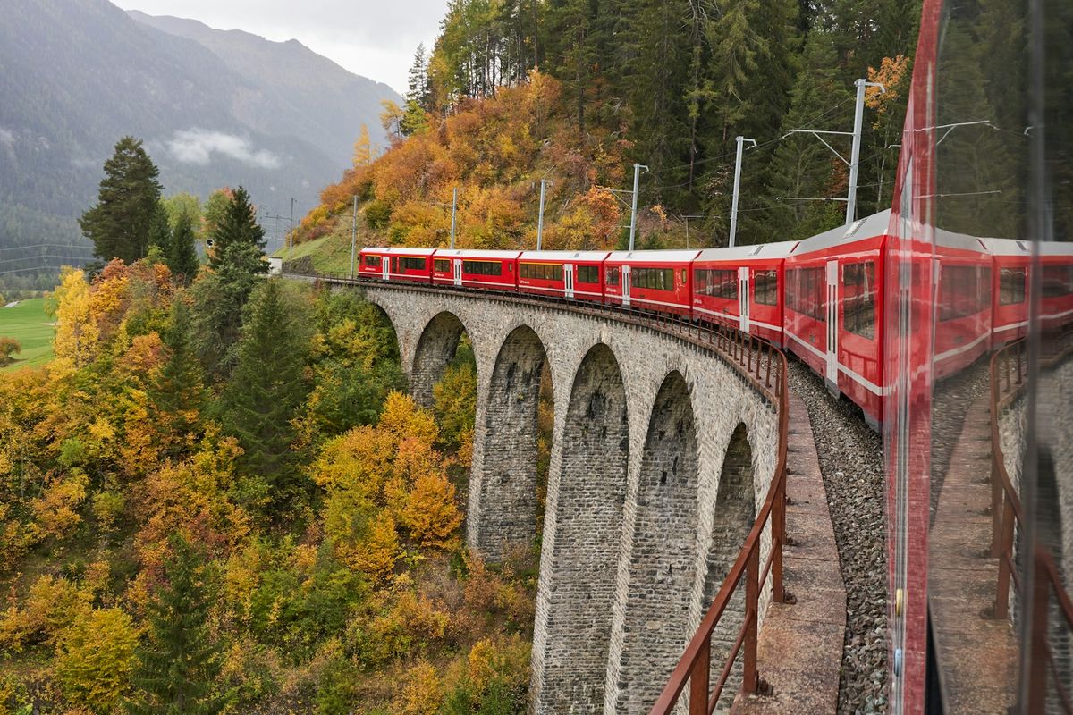 Red panoramic train on railway through Swiss Alps landscape