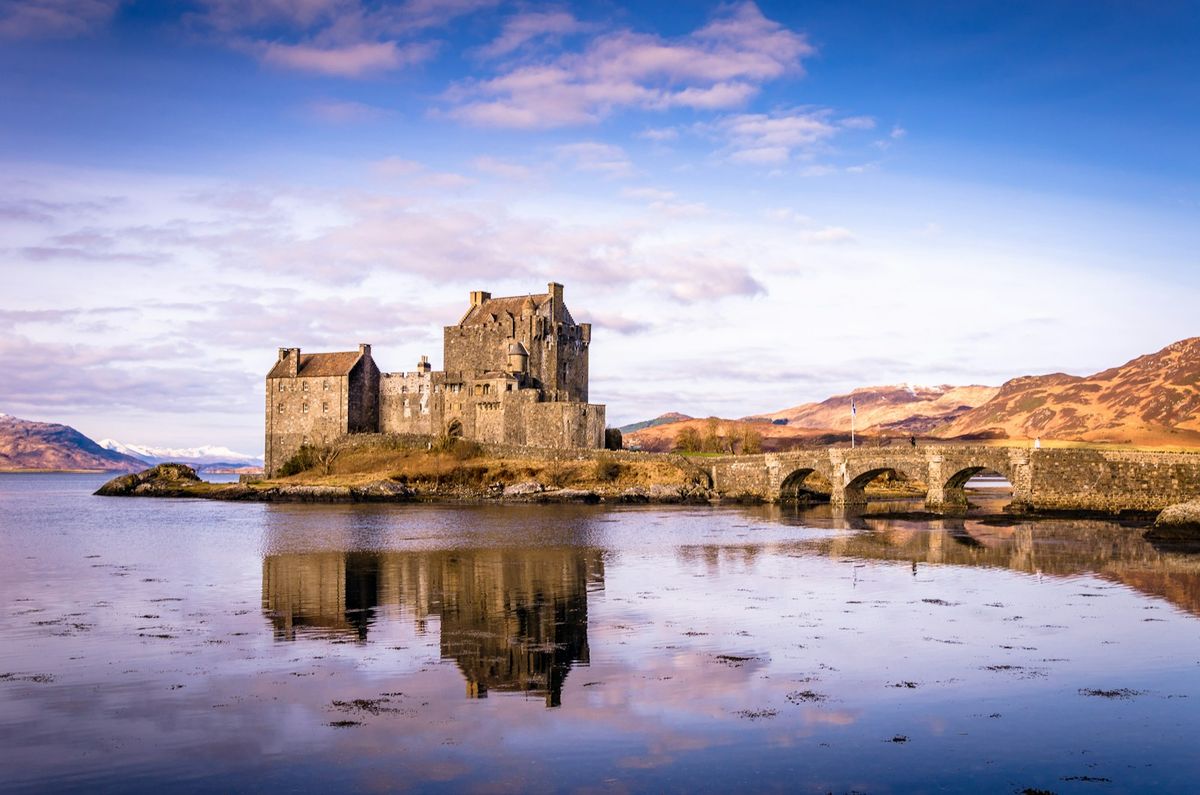 A Highland castle on a loch with mountains behind
