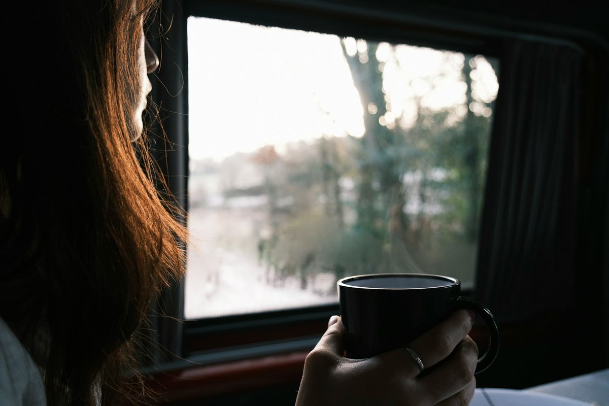 Relaxed traveller holding coffee and looking out a window