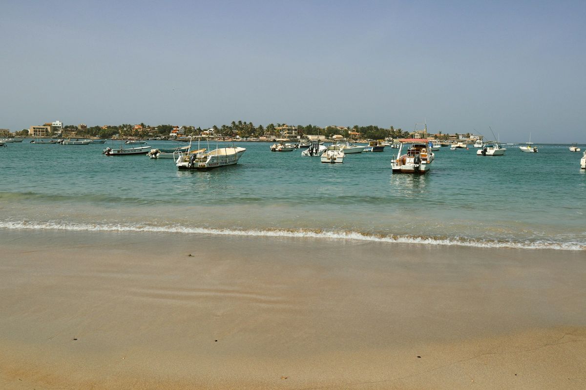 Fishing boats anchored in a calm bay near a West African coastal town